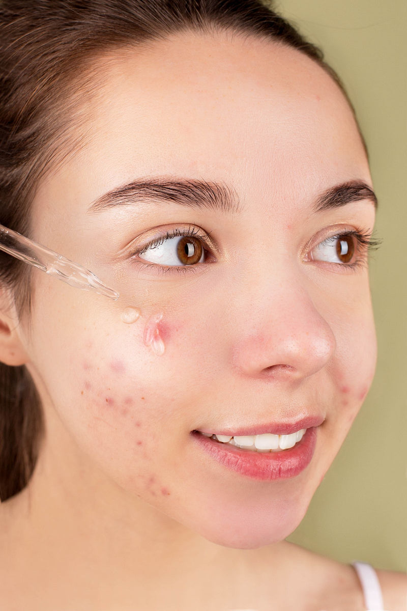 Jeune femme appliquant un sérum sur son visage lors de sa routine de soin du soir