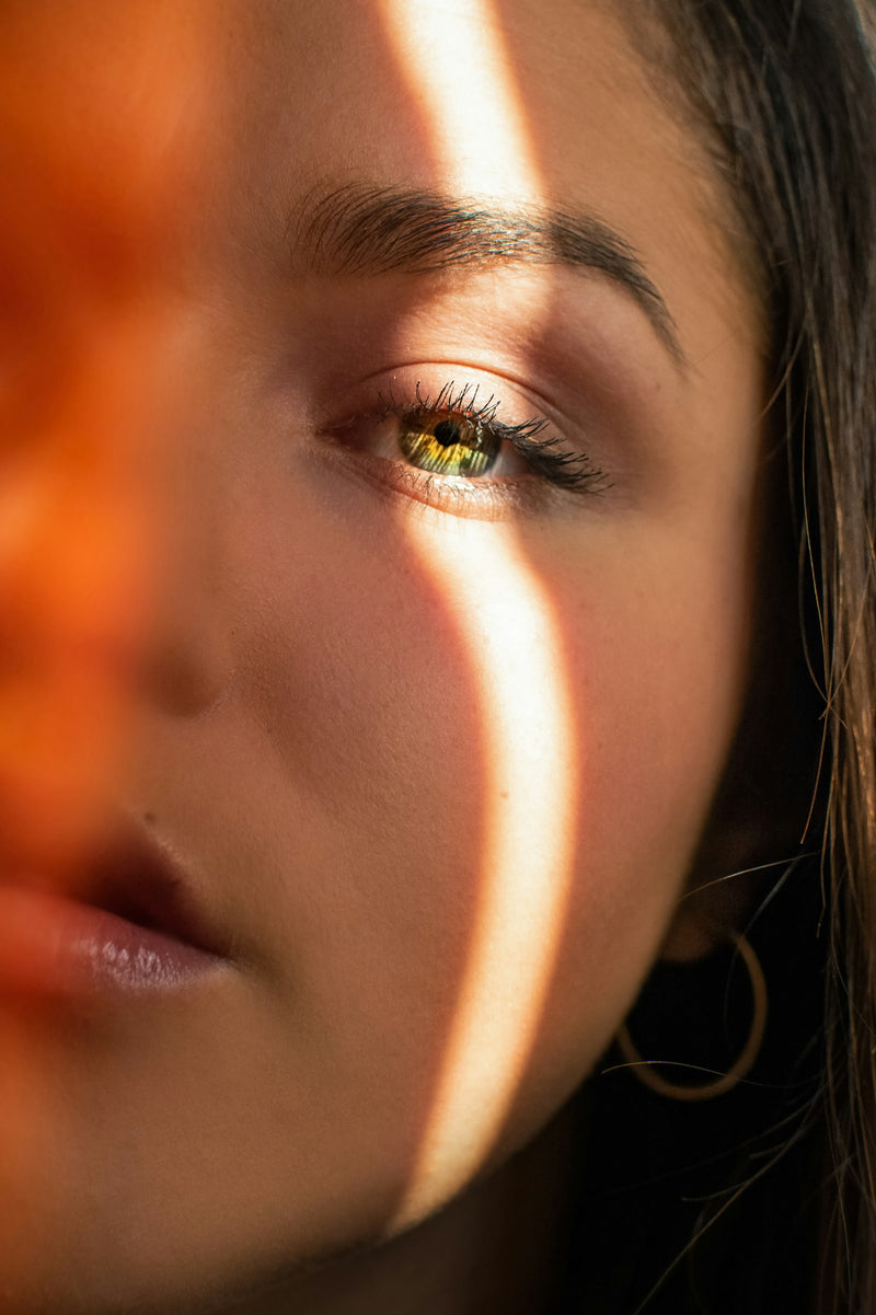 Visage de femme traversé par un rai de lumière solaire sur la joue, évoquant le mélasma déclenché par le soleil