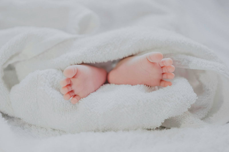 Pieds d'un nouveau-né enveloppés dans une serviette blanche douce