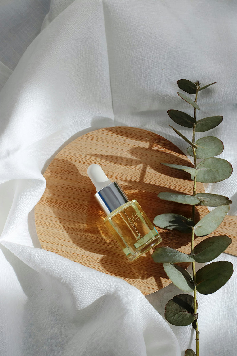 Flacon de sérum avec pipette posé sur un plateau en bois, illustrant les rétinoïdes