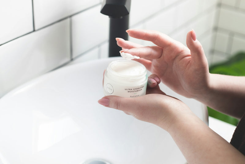 Femme appliquant une crème hydratante sur son visage lors de sa routine de soin