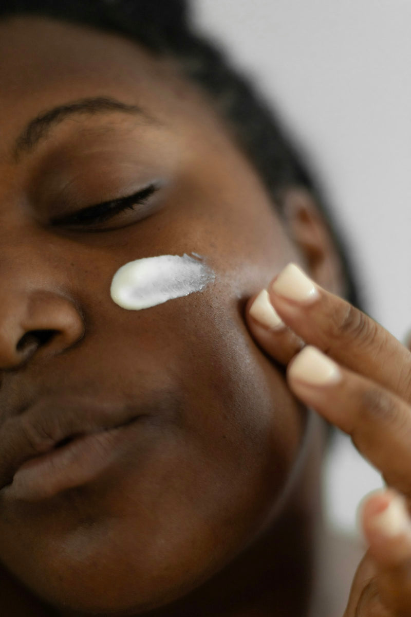 Femme à la peau noire appliquant un soin sur son visage pour prévenir les taches et l'hyperpigmentation